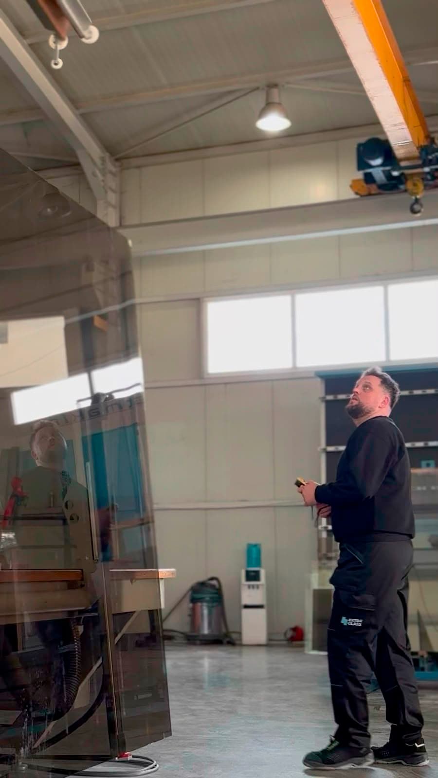 A worker inspecting a large glass sheet in a factory hall